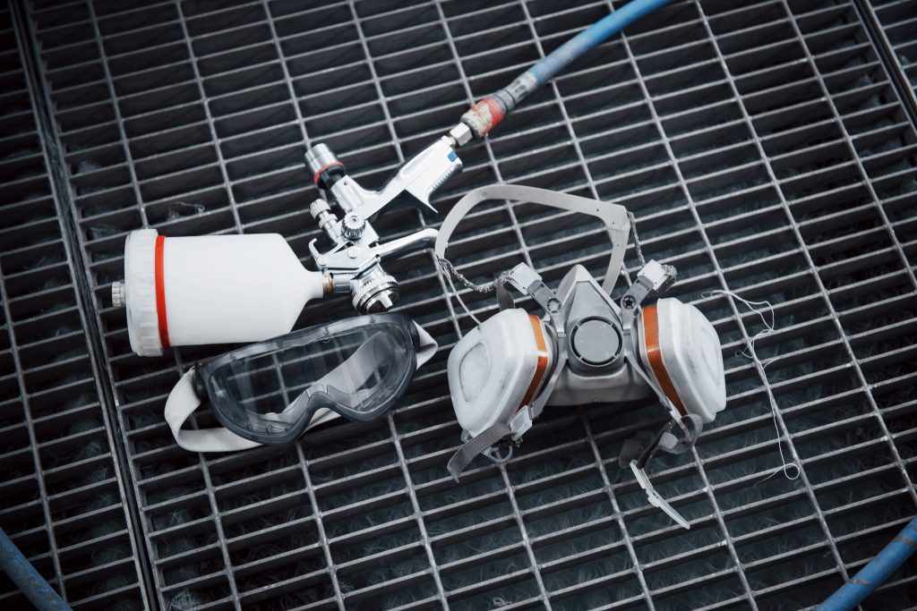 Automotive paint sprayer working in industrial paint booth